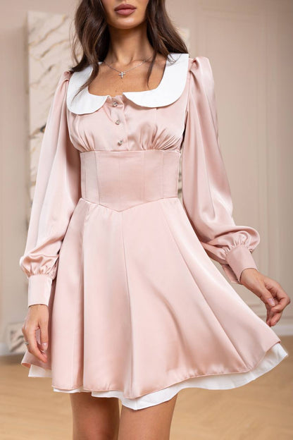 Woman wearing a pink dress with a white collar in an indoor setting