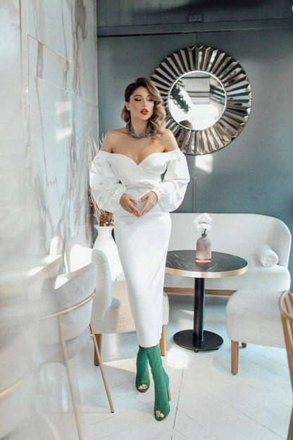 Woman in a white outfit with green shoes in a stylish interior setting