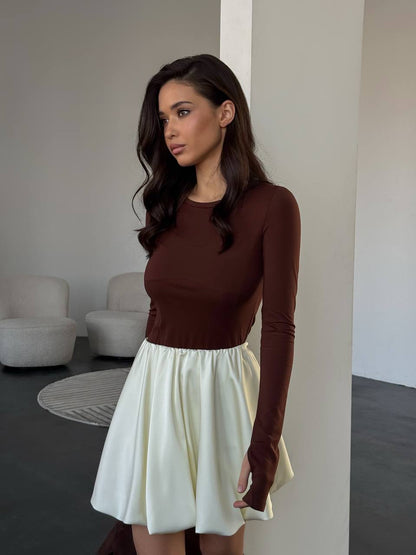 Woman wearing a brown top and white skirt in an indoor setting