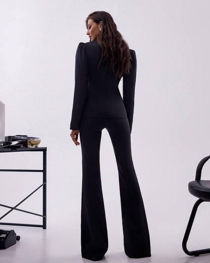 Person wearing a black suit with flared pants in a minimalistic setting