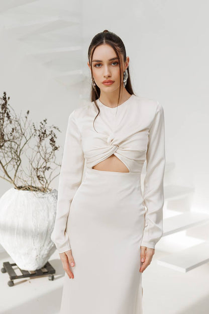 Woman wearing a white dress with a cutout design in a minimalistic setting