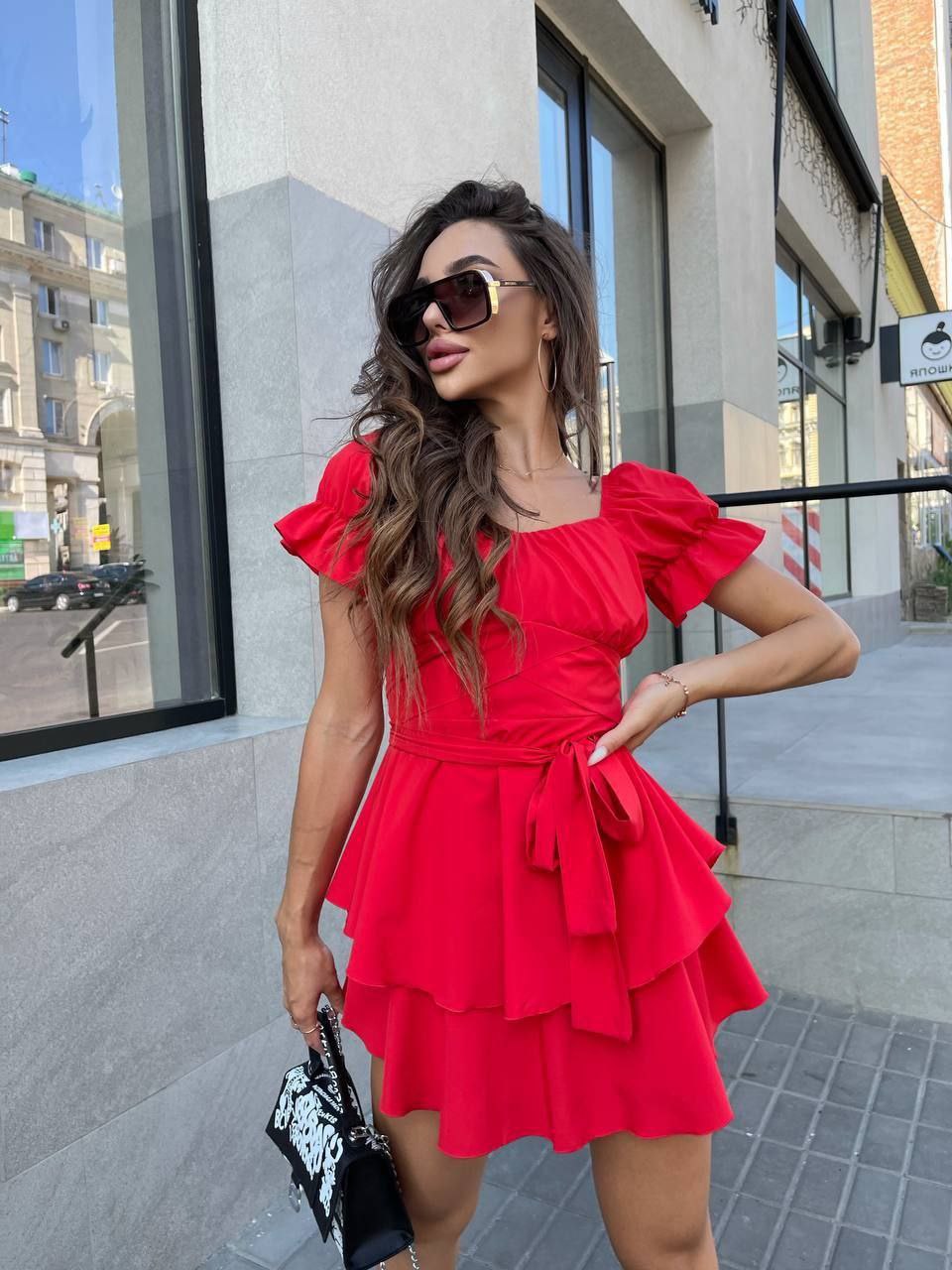 Woman wearing a red dress standing outside a building.