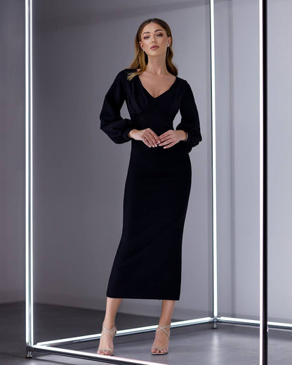 Woman wearing a black dress standing in front of a mirror.