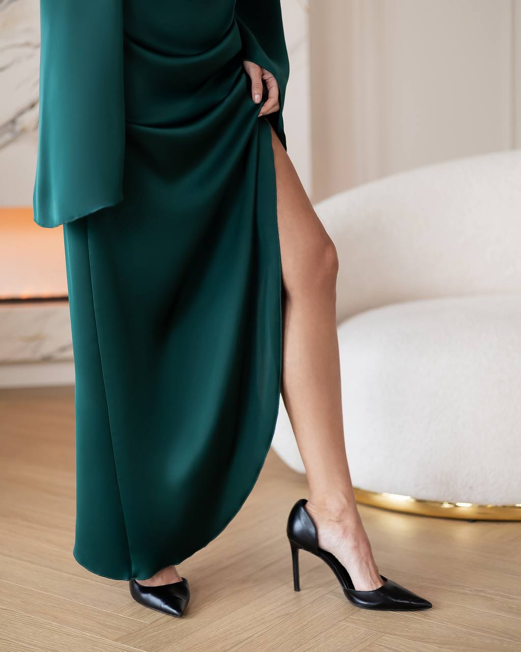 Person wearing a dark green dress with a high slit and black high heels in an indoor setting.