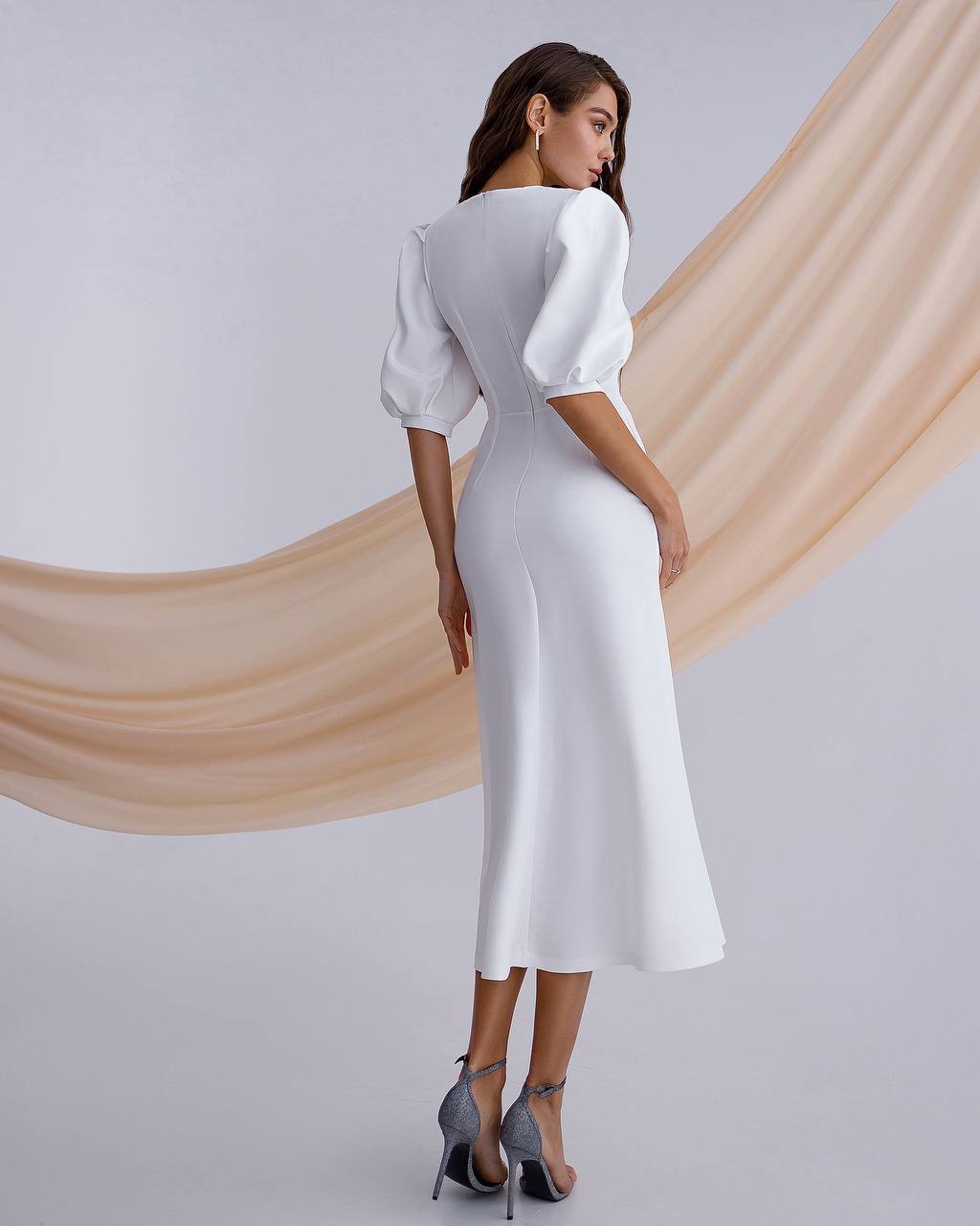 Woman wearing a white dress with a plain background