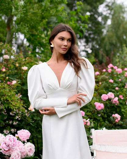 Woman in a white dress standing in a garden with pink flowers