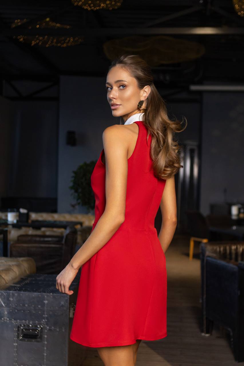 Woman in a red dress standing in an indoor setting with dark decor