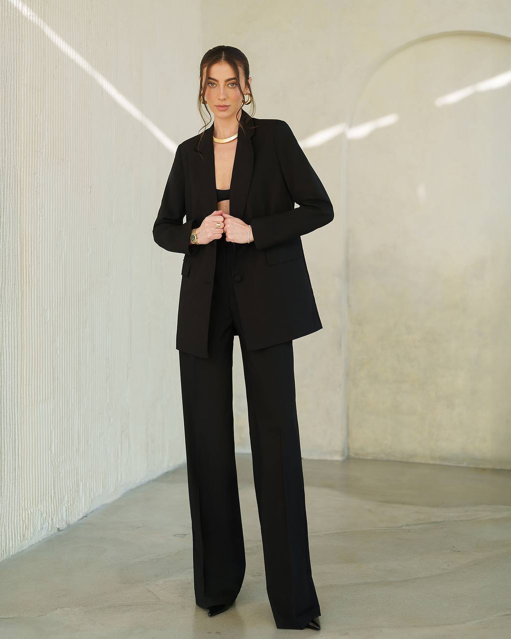 Person wearing a black suit in a minimalistic setting