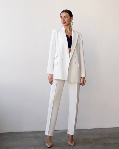 Woman wearing a white suit with a black top against a plain background