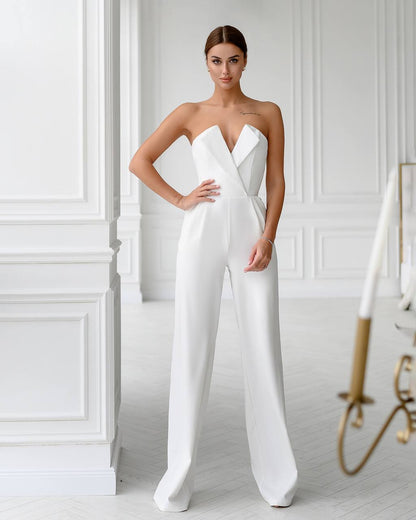 Woman wearing a white strapless jumpsuit in a minimalistic room.