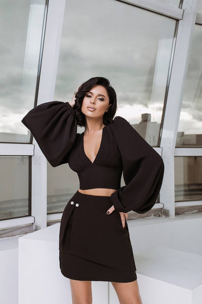 Woman in a black outfit posing in front of a modern building.