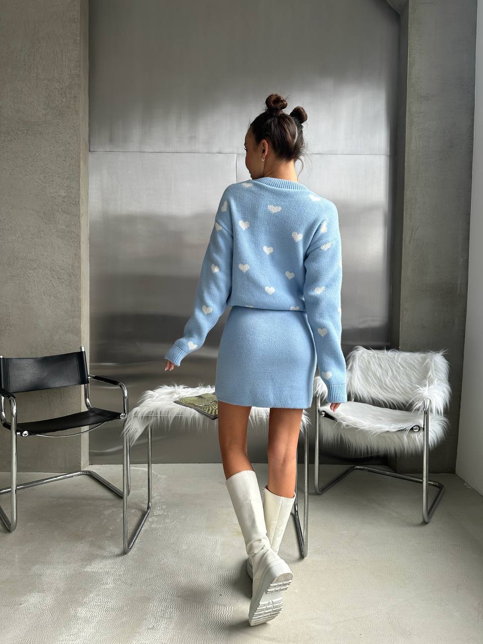Person wearing a light blue outfit with heart patterns in a modern room.