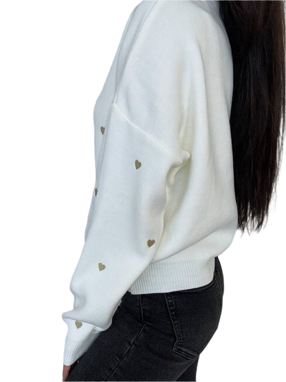 White sweater with gold heart patterns worn by a person on a white background