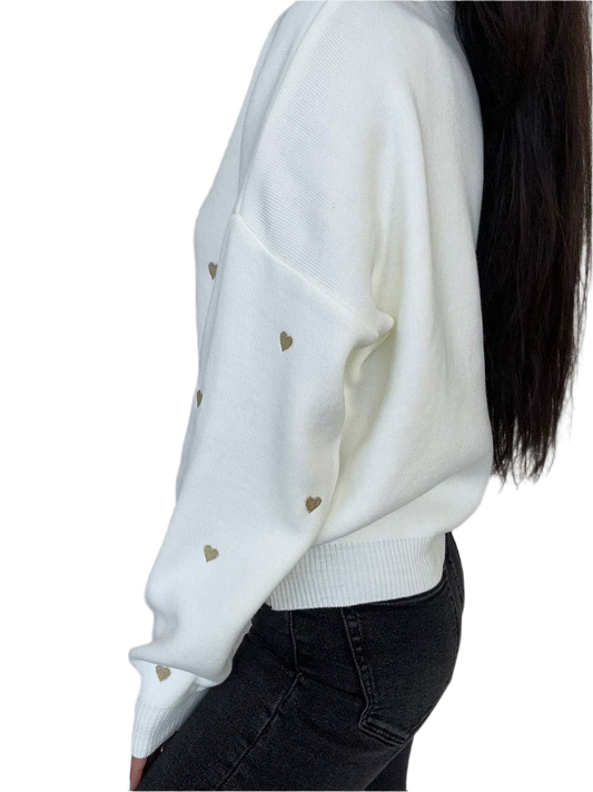 White sweater with gold heart patterns worn by a person on a white background