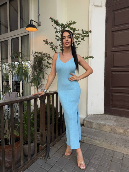 Woman in a light blue dress standing on a patio with plants and a door in the background