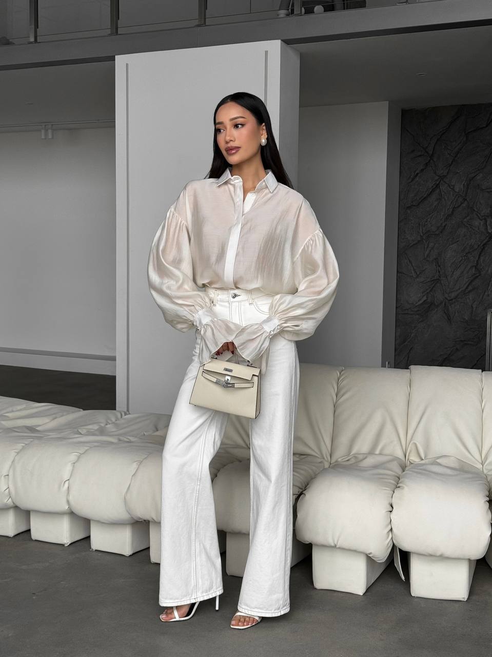 Woman in a white outfit standing in a modern interior setting