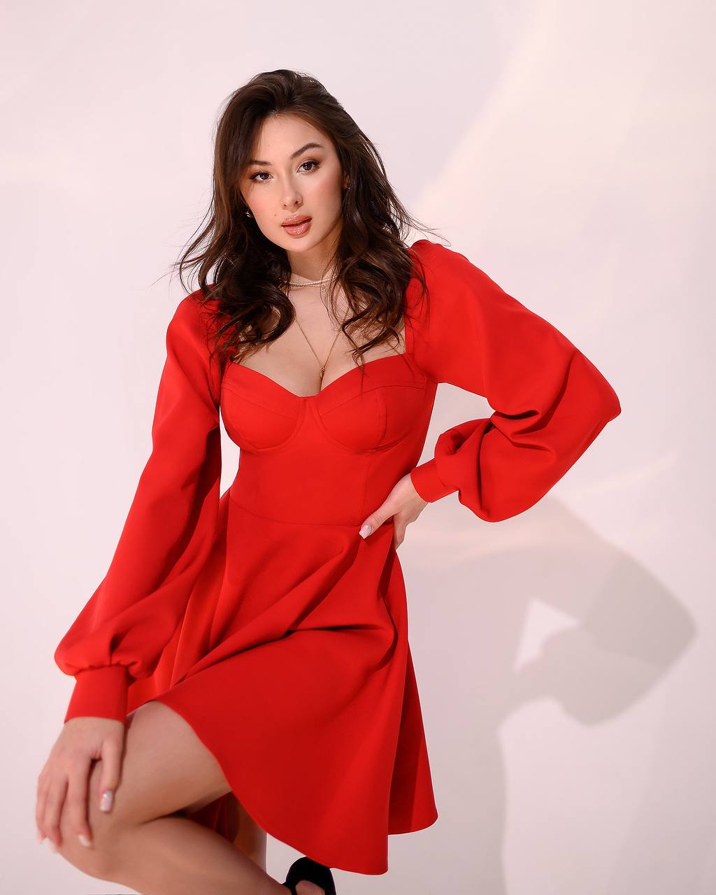 Woman wearing a red dress posing against a white background