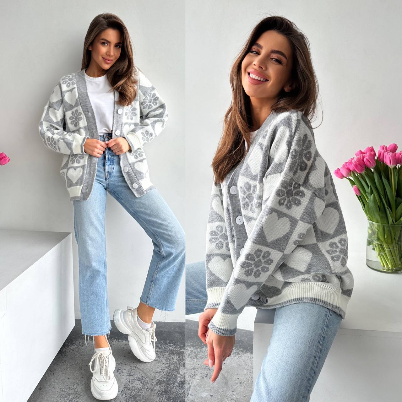 Woman wearing a gray patterned sweater with a white wall and pink flowers in the background