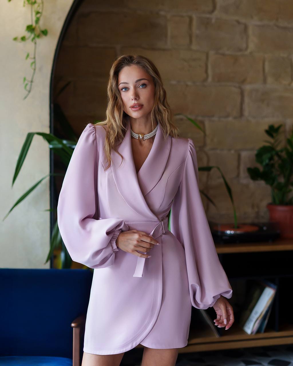 Woman wearing a light purple dress with puffed sleeves in an indoor setting.