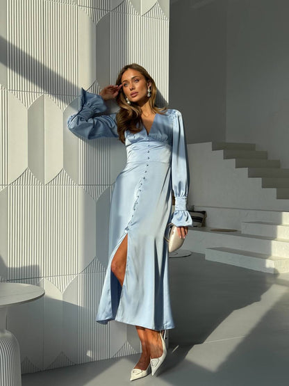 Woman in a light blue dress standing in a modern indoor setting with geometric wall design.