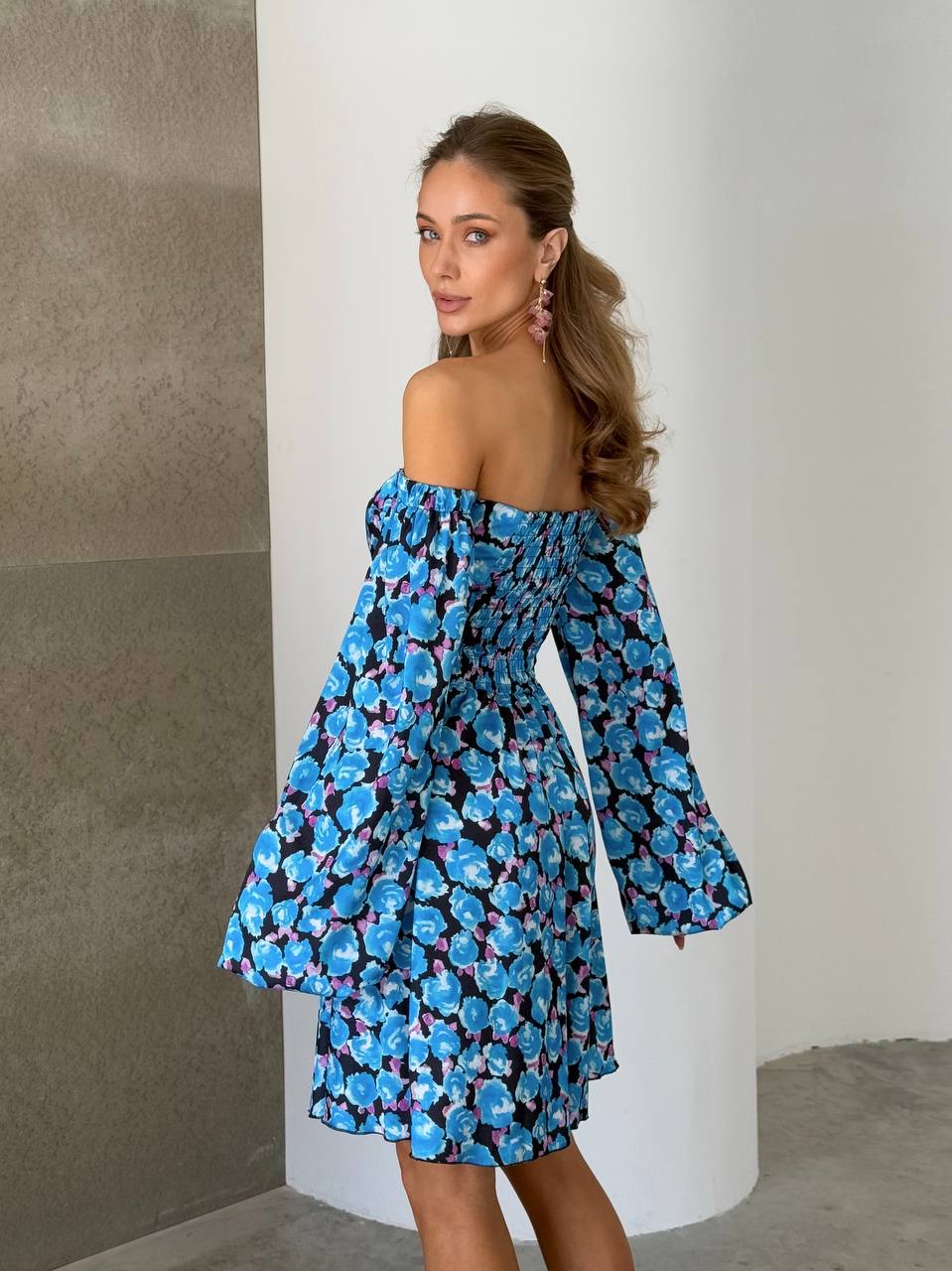 Woman wearing a blue floral dress with long sleeves against a neutral background