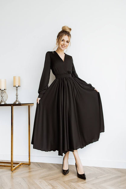 Woman wearing a black dress in a room with a table and candles.