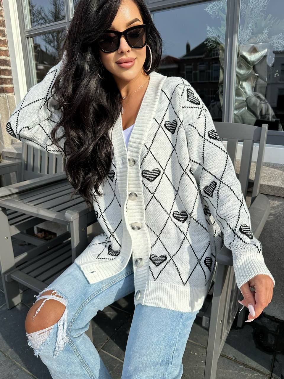 Woman wearing a patterned cardigan and ripped jeans outdoors.