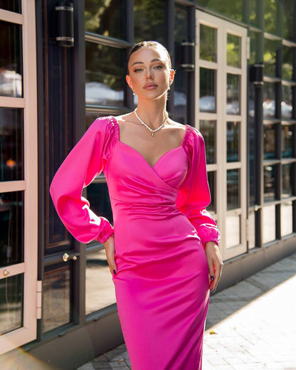 Woman in a bright pink dress standing outdoors near a building.