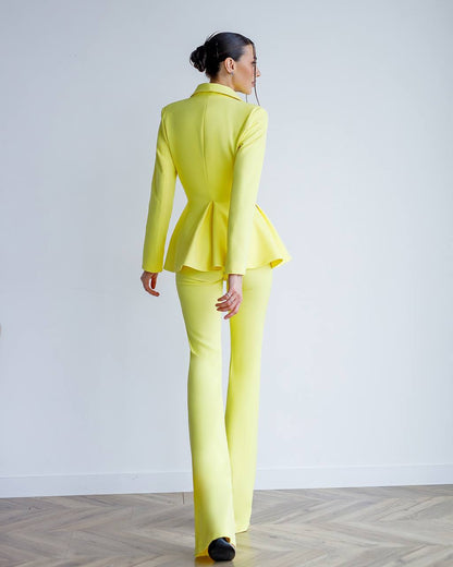 Woman wearing a bright yellow suit standing against a plain white background