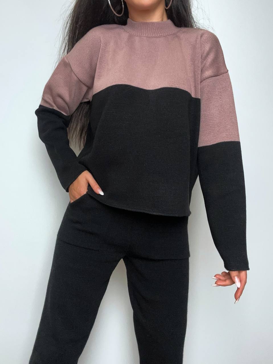 Person wearing a two-tone sweater with pink and black colors on a white background