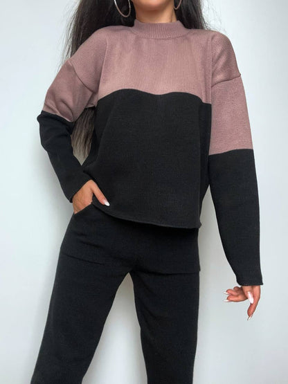 Person wearing a two-tone sweater with pink and black colors on a white background