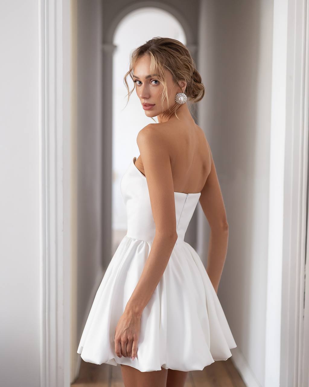 Woman wearing a white strapless dress in an elegant interior setting