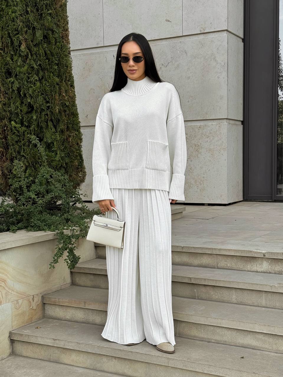 Woman in a white outfit standing on steps outdoors