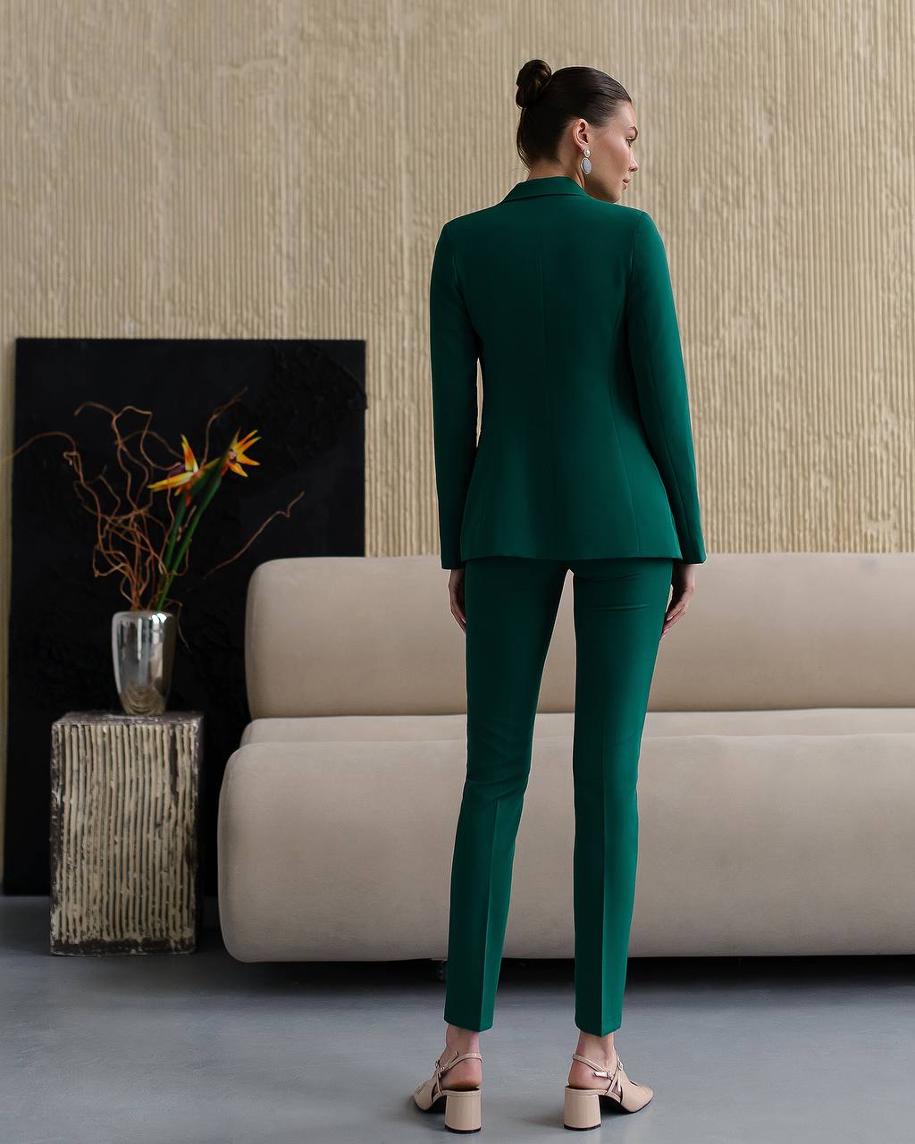Woman wearing a green suit standing in a modern living room.