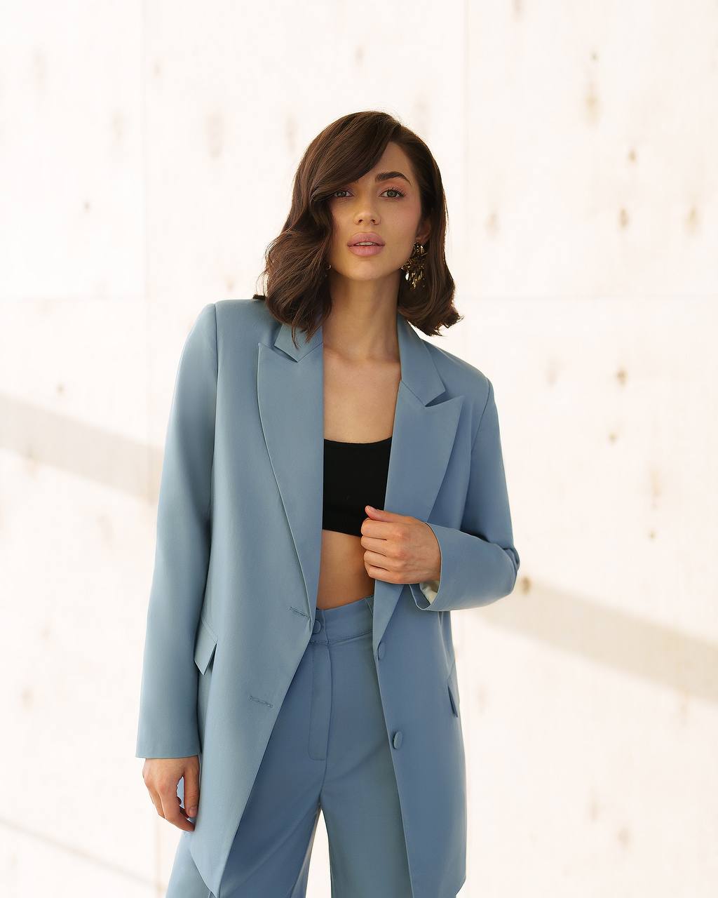 Woman wearing a light blue suit with a black top against a white background