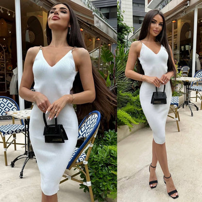 Woman in a white dress standing outdoors with tables and chairs in the background.