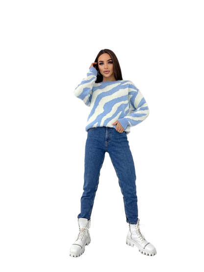 Person wearing a blue and white striped sweater with blue jeans on a white background