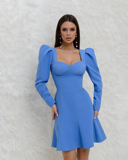 Woman wearing a blue dress with puffed sleeves against a white background