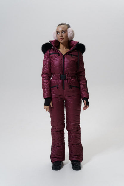 Person wearing a maroon snowsuit with fur-lined hood and pink ear muffs on a white background
