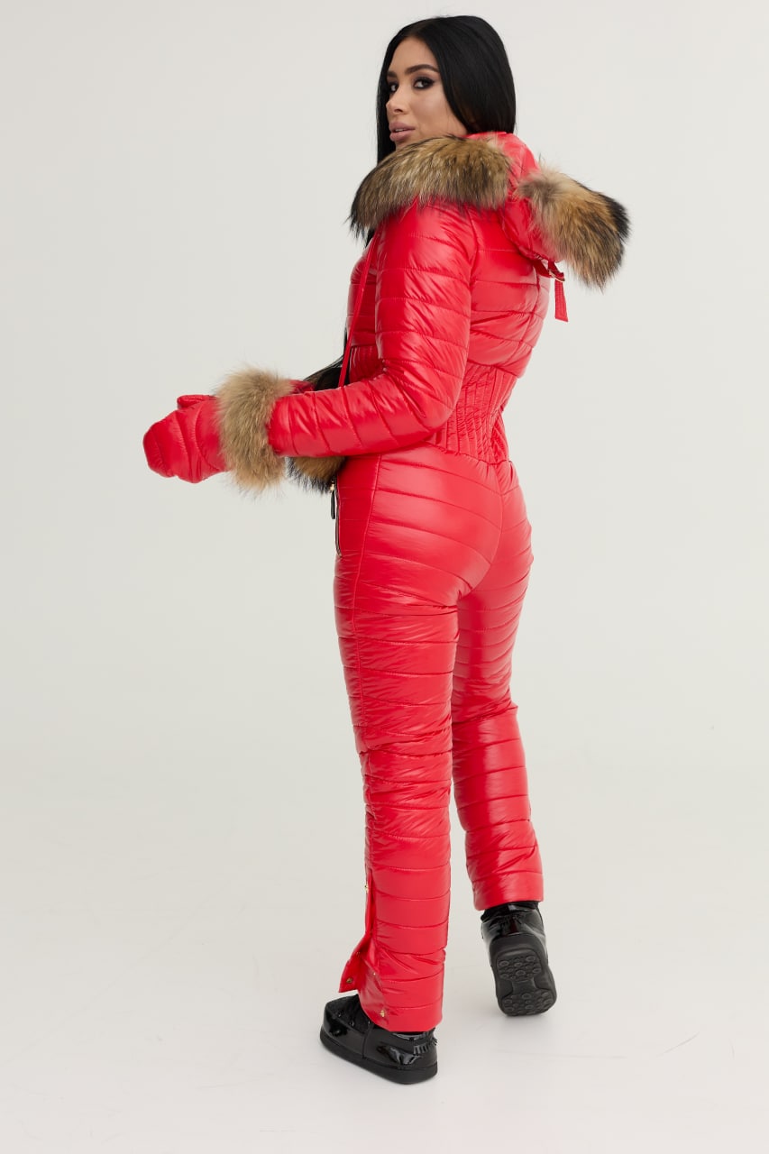 Person wearing a red puffer jumpsuit with fur trim on a white background