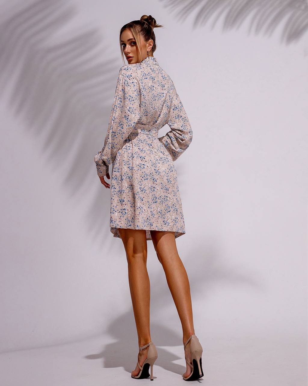 Woman wearing a floral dress against a plain background