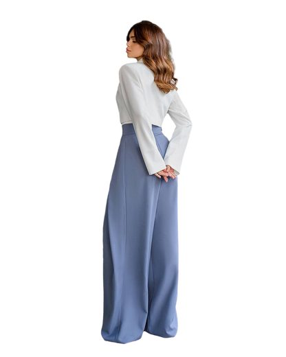 Woman wearing a white blouse and blue wide-leg pants on a white background