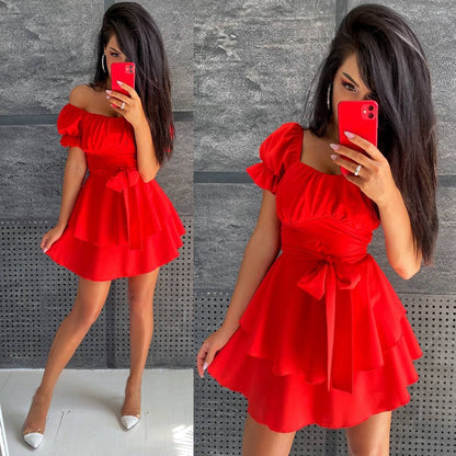 Woman wearing a red off-shoulder dress with a bow detail, taking a mirror selfie.