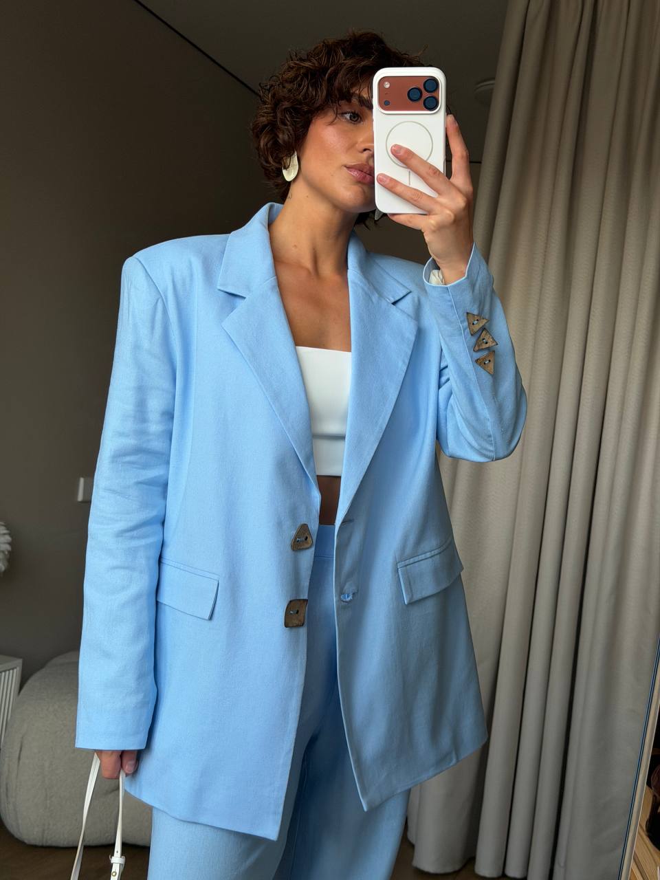 Person wearing a light blue suit taking a mirror selfie.