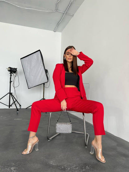 Woman in a red suit sitting in a studio setting with photography equipment.