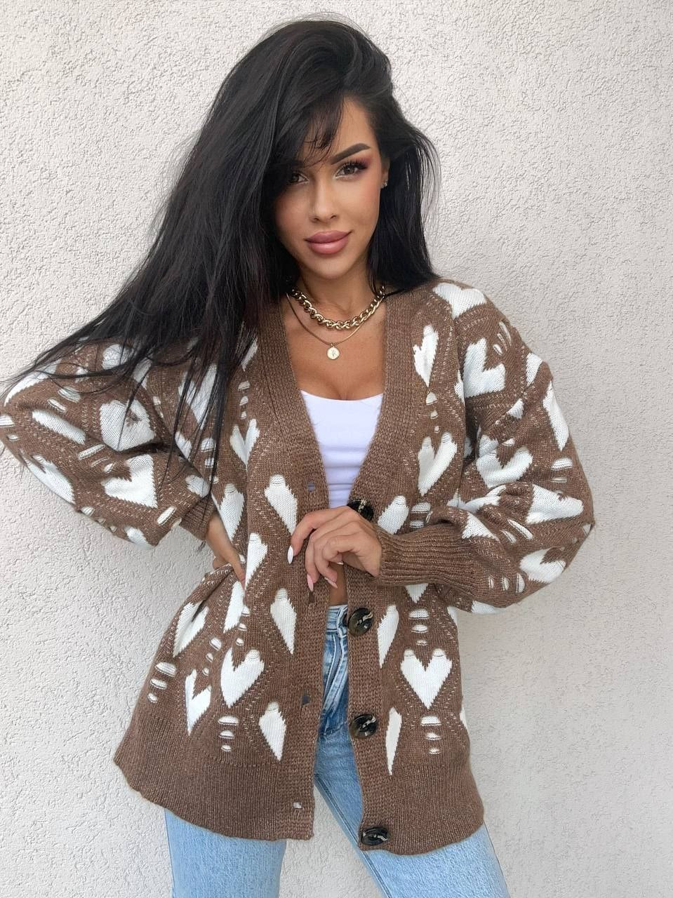 Woman wearing a brown cardigan with white heart patterns against a light background