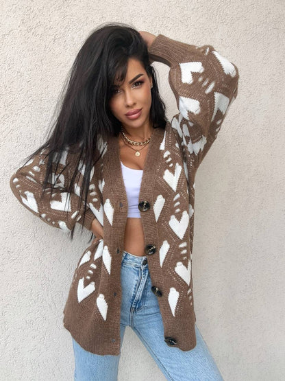 Woman wearing a brown cardigan with white patterns against a beige wall