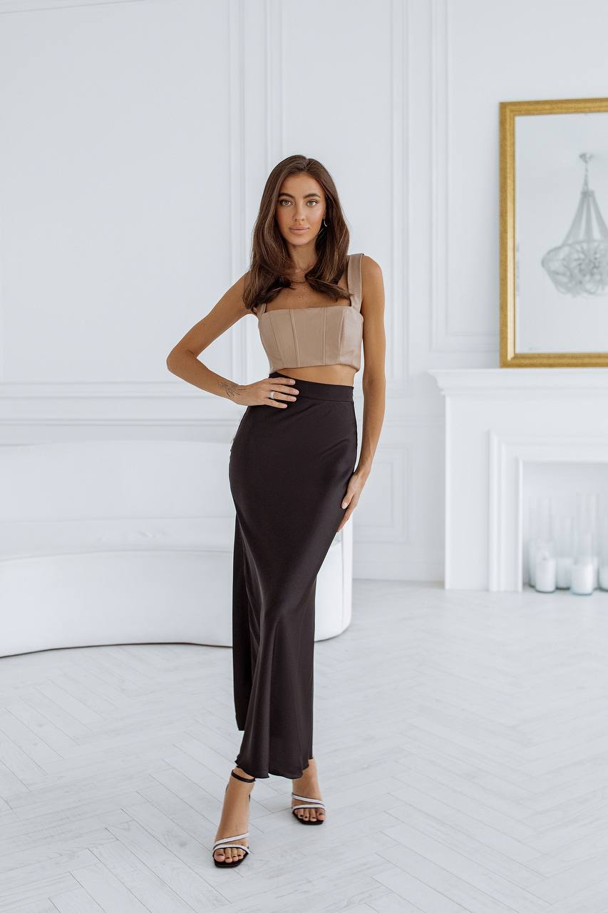 Woman wearing a beige top and black pants in a room with white walls and a fireplace.
