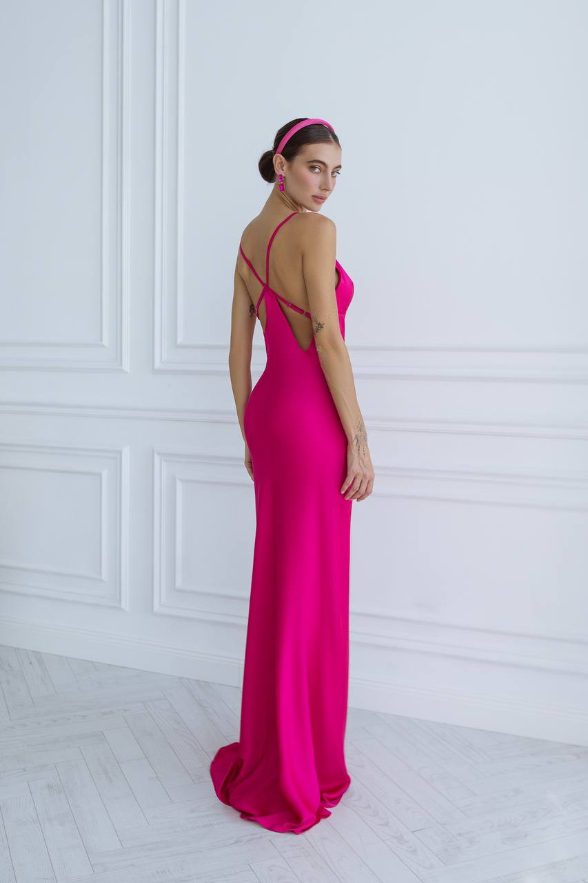 Woman wearing a bright pink evening gown with a white wall background