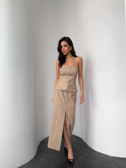 Woman wearing a beige strapless top and skirt against a plain background